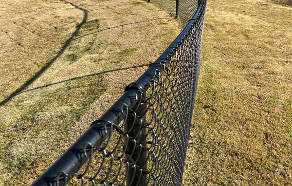 Black PT15 round fence tubing used in a chain link fence